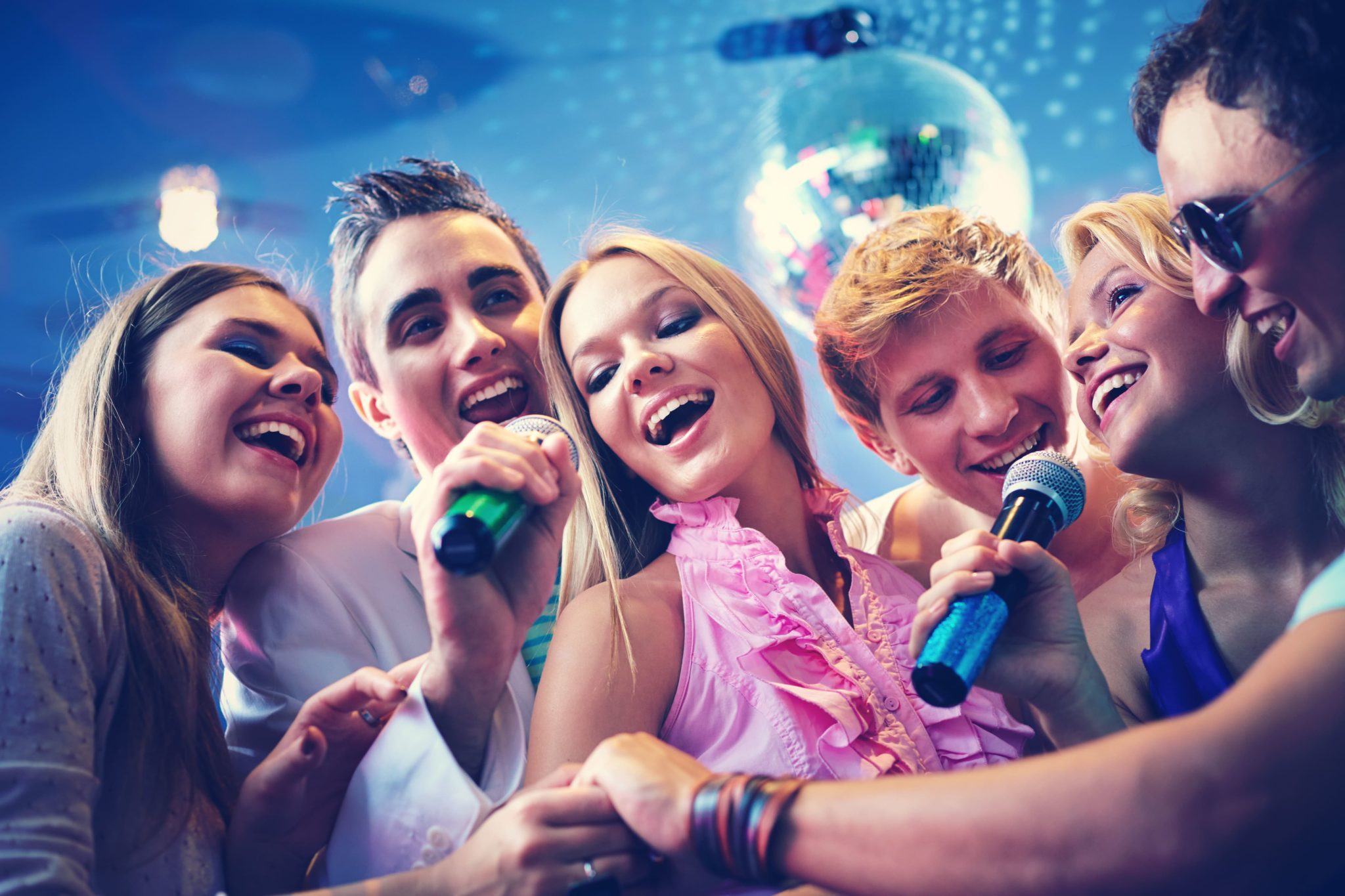 chicos y chicas cantado juntos con micrófonos en la mano en karaoke