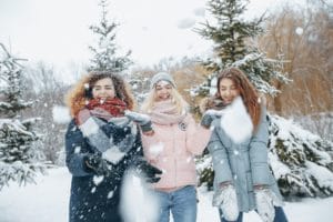 3 amigas sonriendo en la nieve muy abrigadas